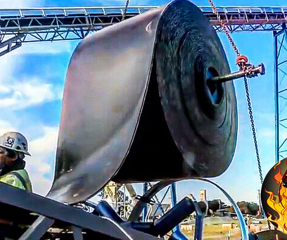 crane pulling rolled conveyor belt up for installation of the conveyor belt.